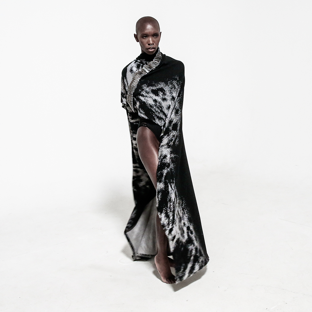 front view model in safety pin cape wrapped around body over white background