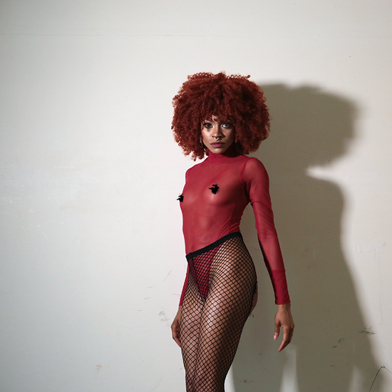 front view red hair model red sheer mesh see through transparent bodysuit in fishnet stockings over white background